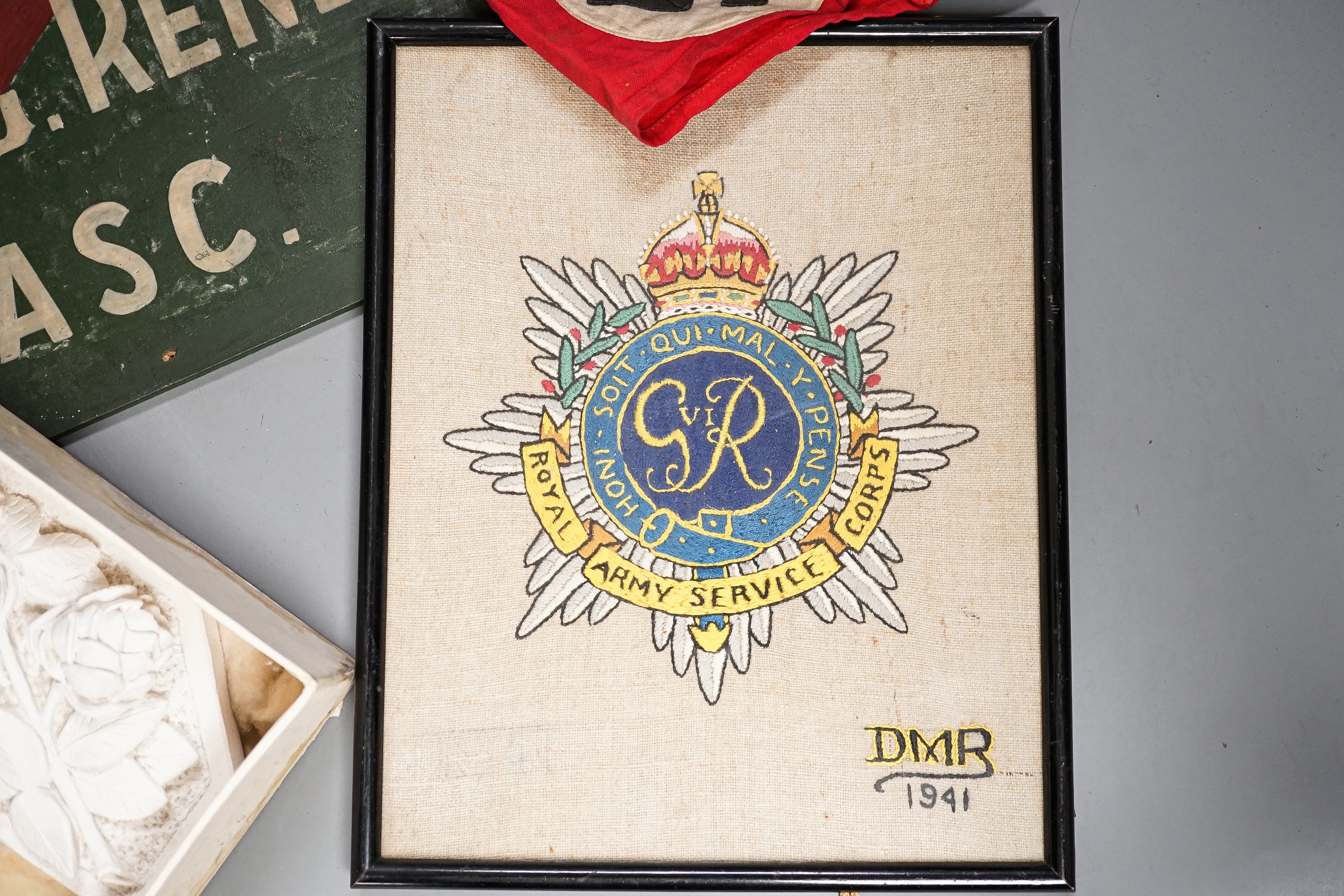 A group of WWI and WWII militaria badges, buttons, two swagger sticks, an armband and a World War I German POW inscribed plaster ornament, longest swagger stick 70 cms long.